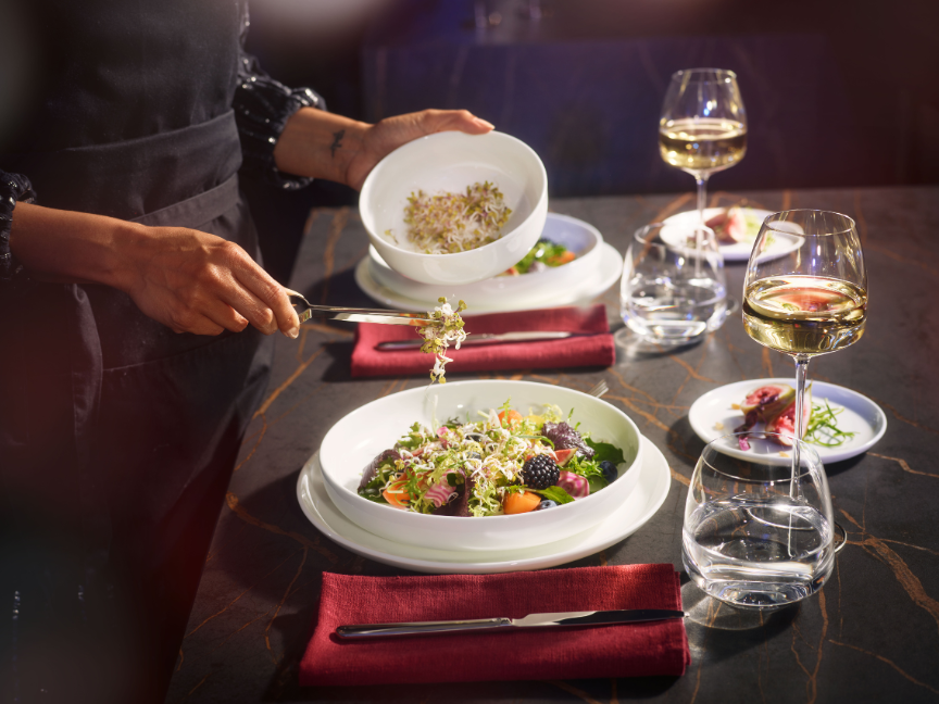 Eleganter gedeckter Tisch mit Bone China Porzellan von Rosenthal: Feine wei&szlig;e Teller mit kunstvoll angerichteten Speisen und stilvollem Ambiente f&uuml;r besondere Genussmomente.